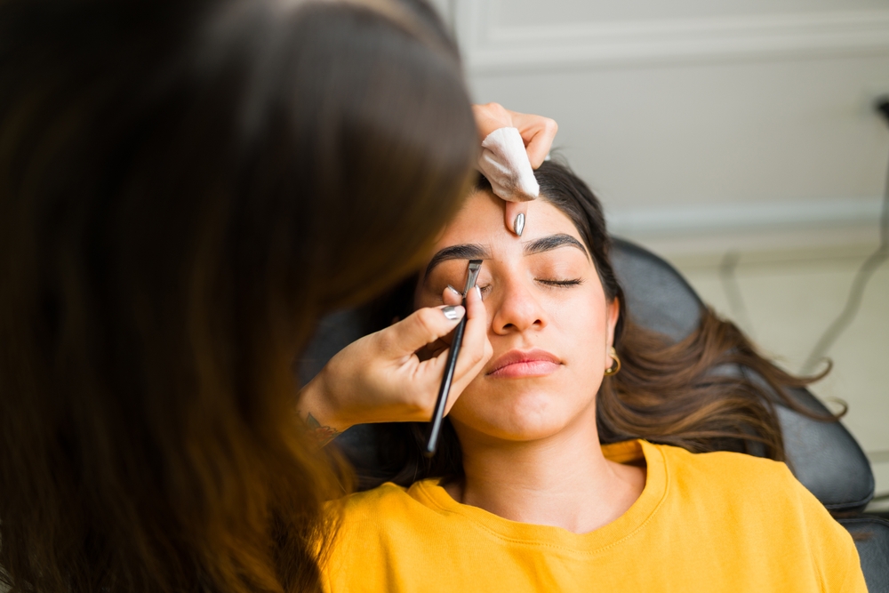 Client getting her brows done by a cosmetologist student