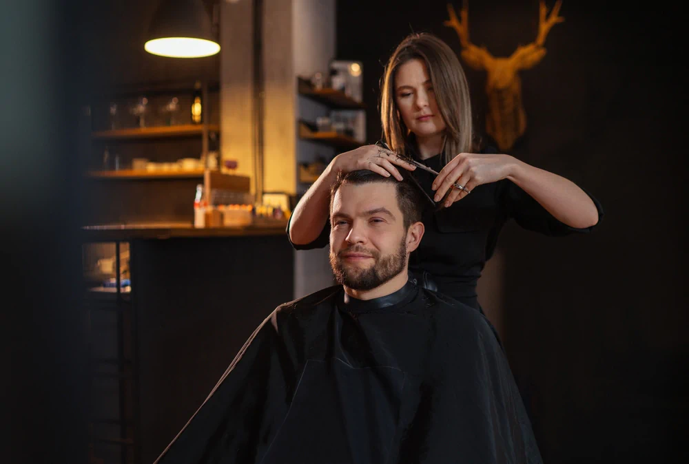 Female barber cutting man’s hair