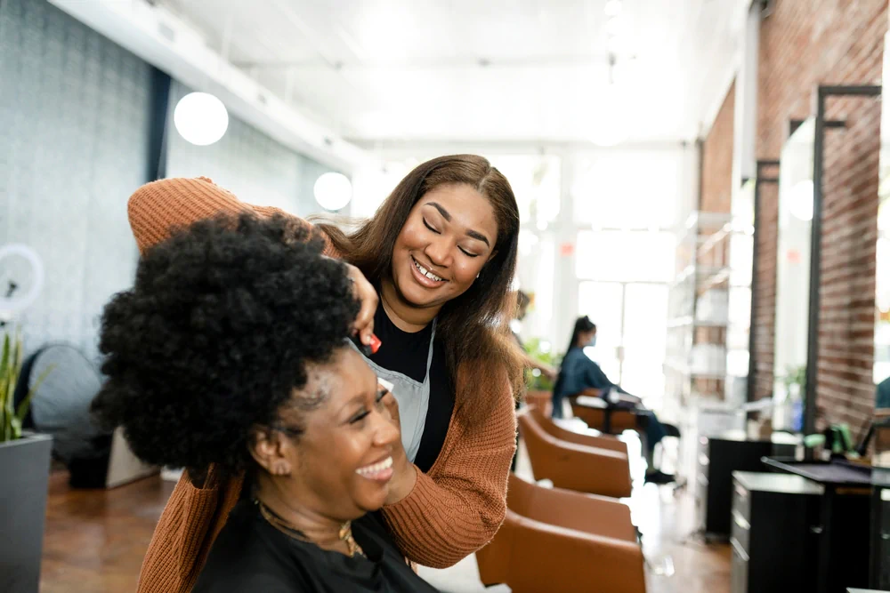 Hairstylist working on a client with natural hair