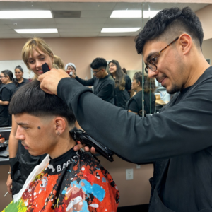 Future licensed barber precisely styling and trimming a client's hair during training.