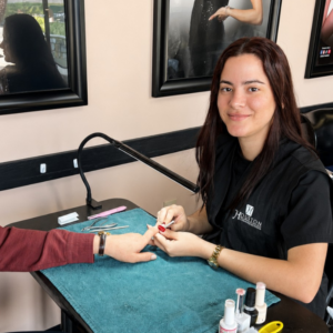 Nail technician student practicing a professional manicure and nail care treatment on a client in a beauty school clinic.